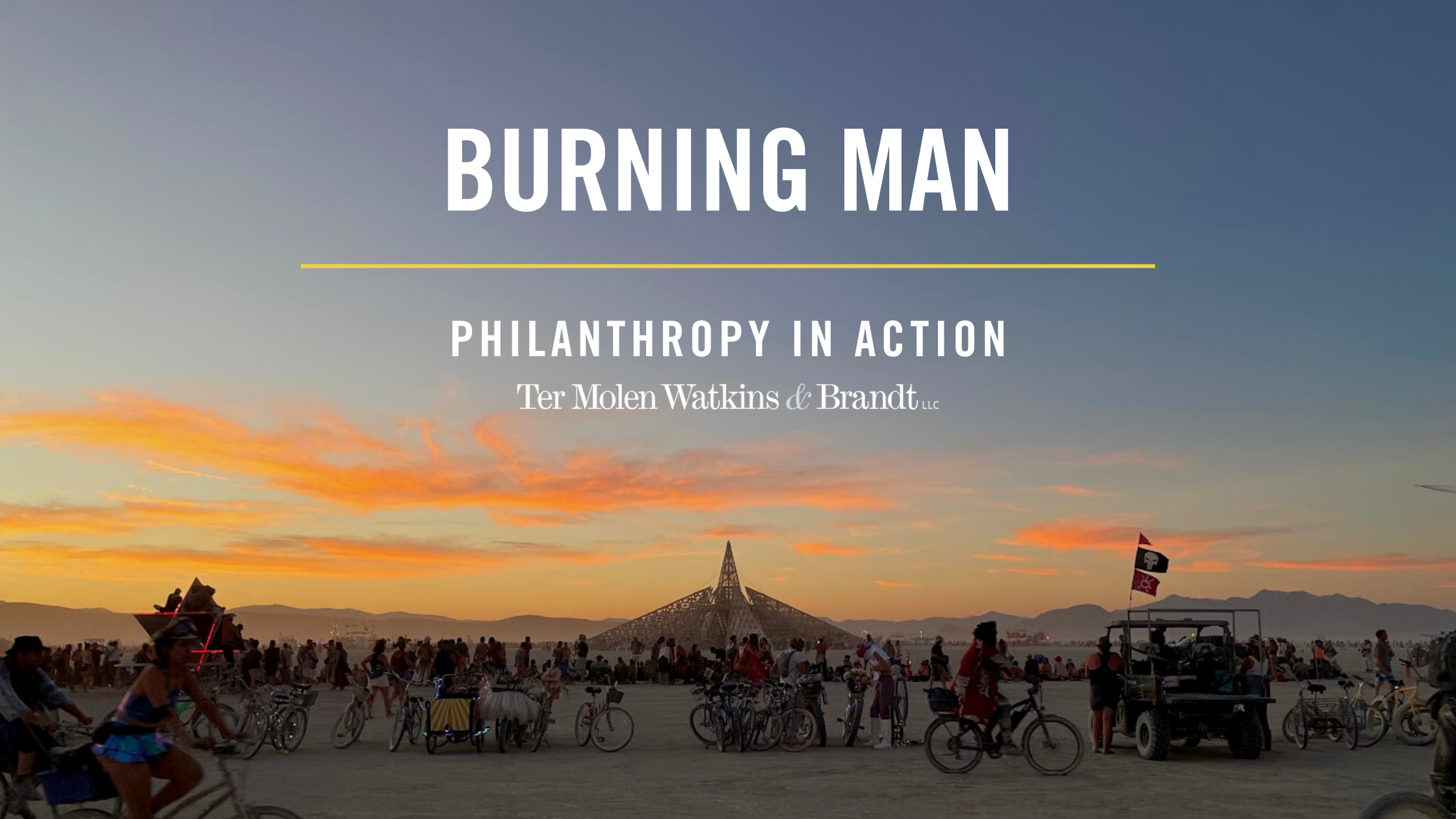 A photo banner of an image from Burning Man at sunset. In the background is a temple-like statue, with people walking and bike riding in front of it.